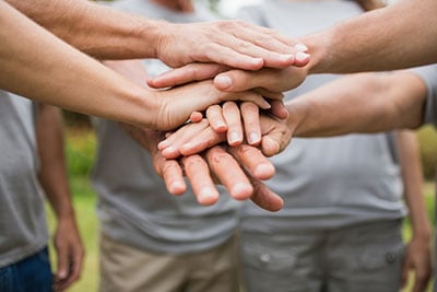 Group of people stacking their hands in unity. 