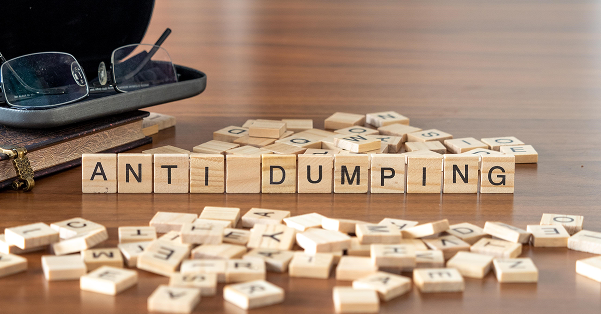 anti dumping word or concept represented by wooden letter tiles on a wooden table with glasses and a book