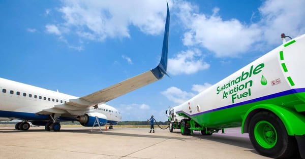 A fueling tanker labeled Sustainable Aviation Fuel filling up a commercial aircraft with renewable fuel.