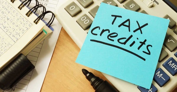 Work desk with a post-it note on a calculator which reads tax credits.