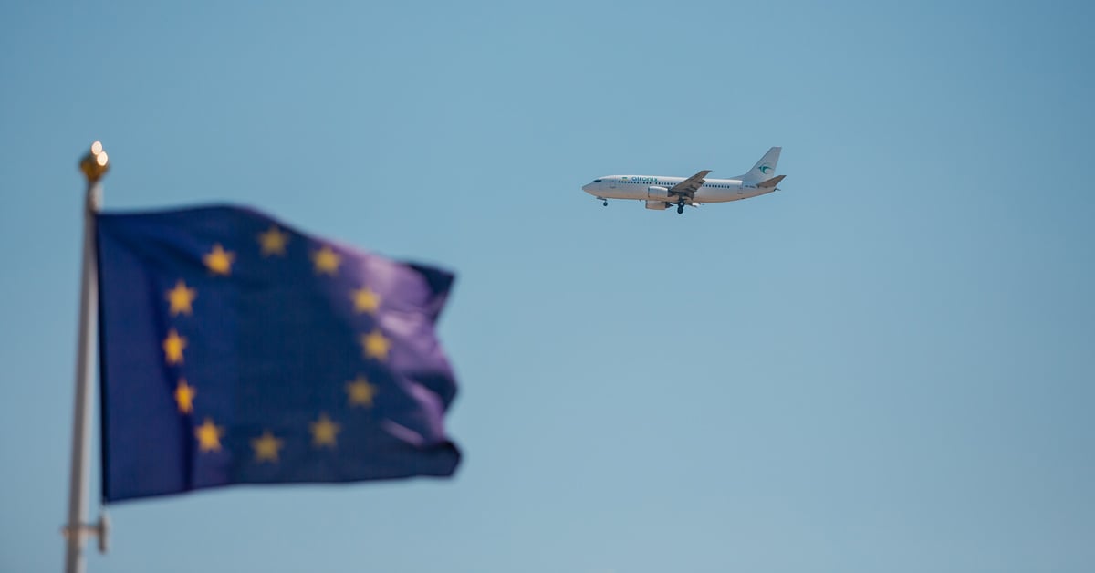 An airplane flying in the sky with the EU flag in the foreground.