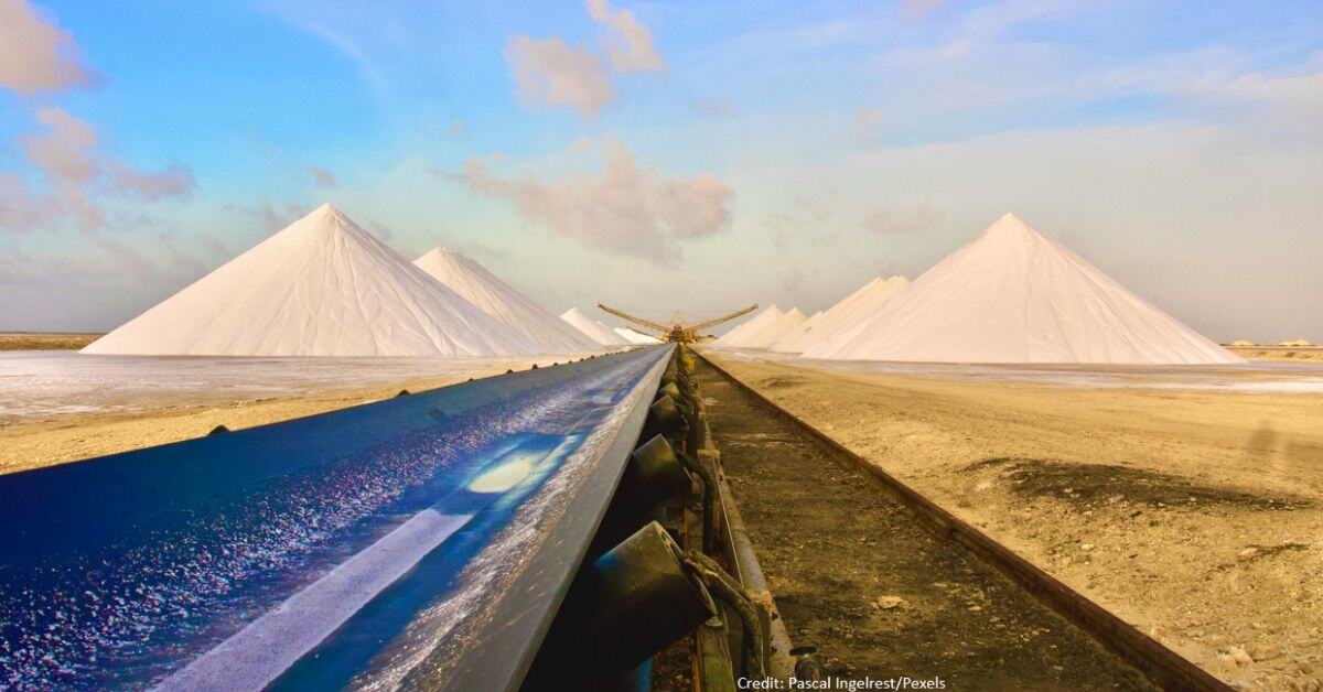Mountains of sea salt and a lifting crane in the middle in a scene of a salt mine. 
