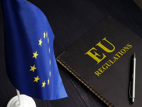 Small flag of the European Union next to a notebook titled "EU Regulations."