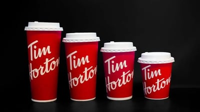 Five Tim Horton's red paper coffee cups in a row.