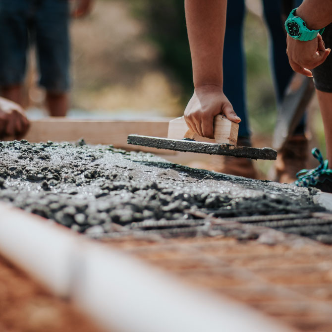 Close-up of a worker pouring concrete at an industrial building site. 