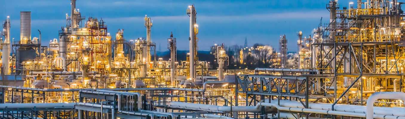 Chemical manufacturing plant with lights on at dusk. 