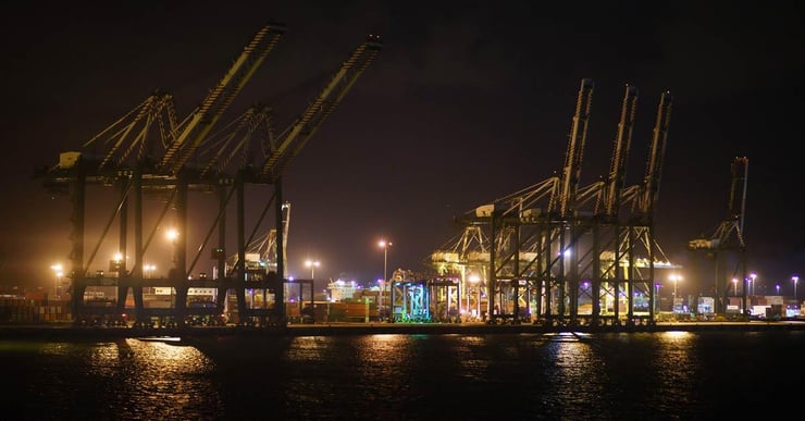 A Panamanian port with large cranes, illuminated in the night.