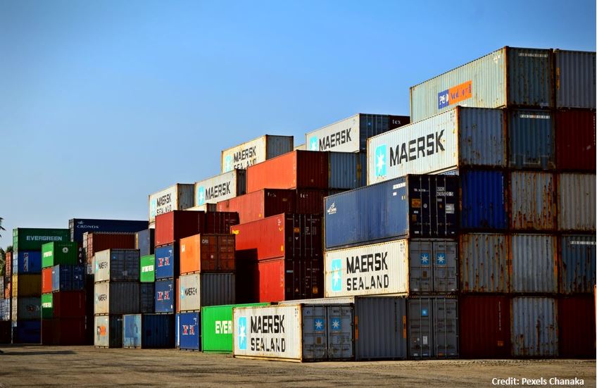 Several dozen colorful cargo and shipping containers stacked up at a port location. 