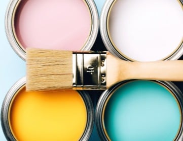 Image shows a paintbrush overlaid on four pots of paint 