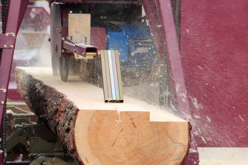 A sawlog being processed into lumber cuts using cutting tools.