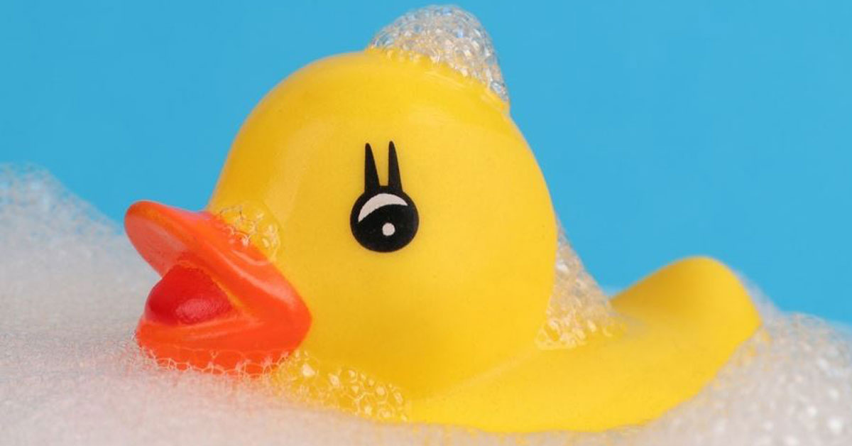 Rubber ducky in a bathtub with a blue background. 