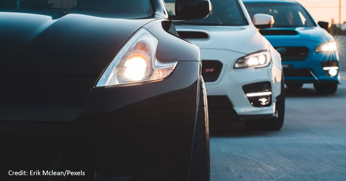 Three new cars with their headlamps shining in a row. 