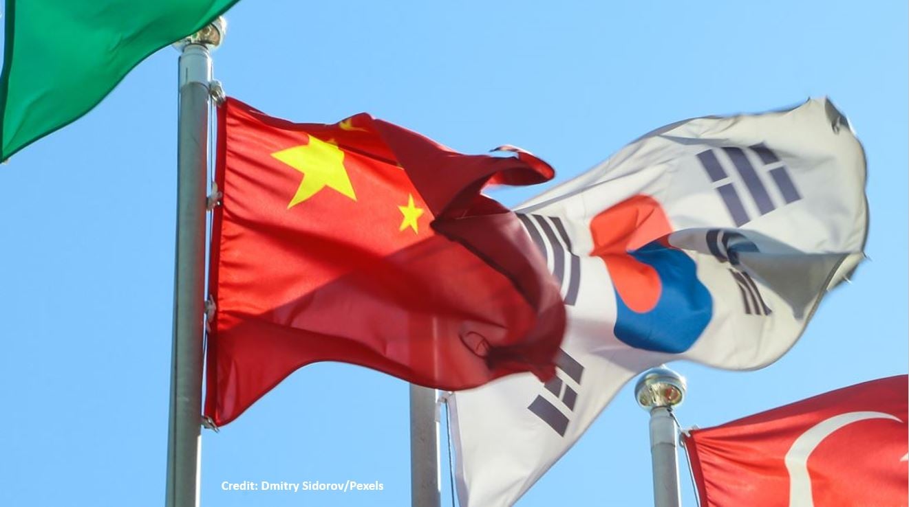 A South Korean flag waves in the wind in the background of China's ensign.